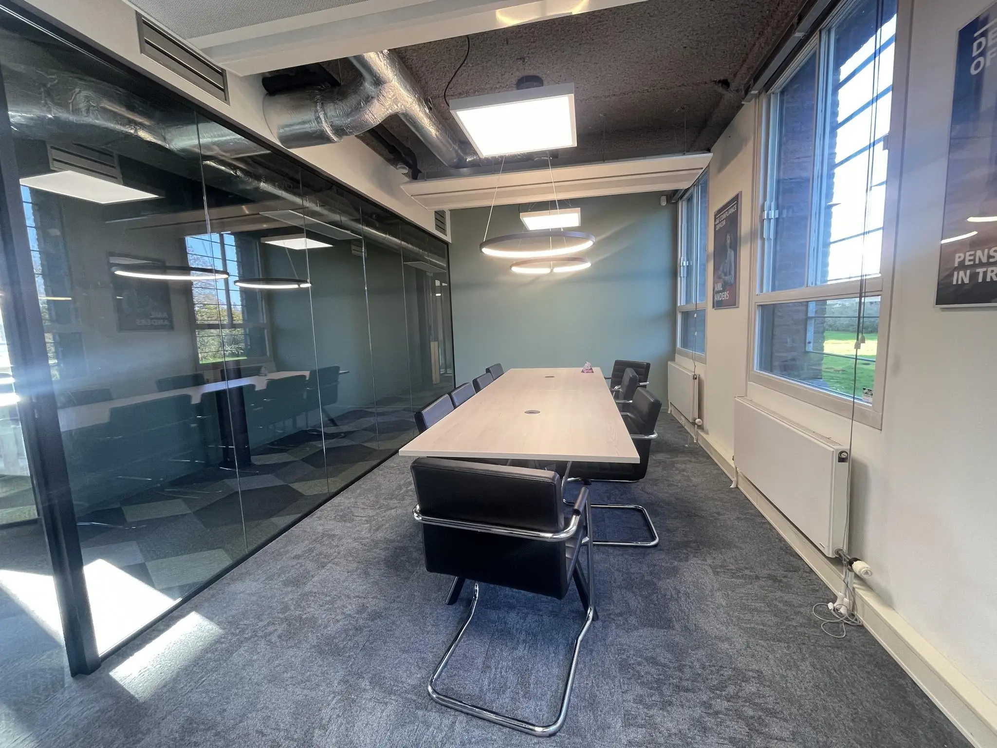 Moderne vergaderruimte aan de Jan Leentvaarlaan met lange tafel, zwarte stoelen en glazen wand.